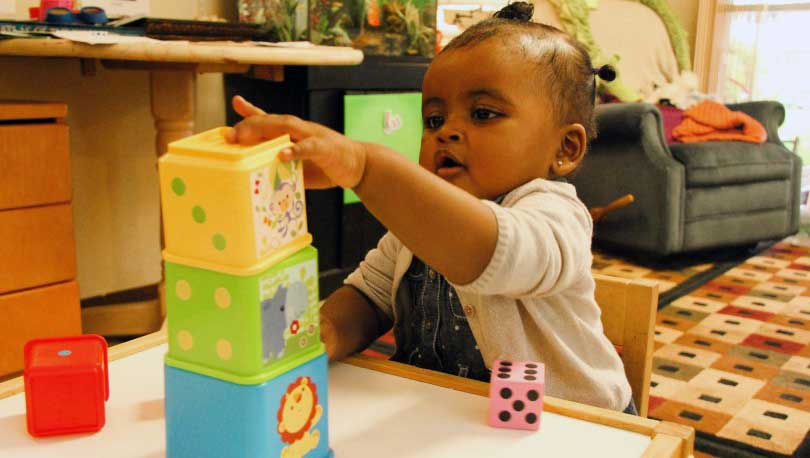 Toddler completed putting the last stacking block on.