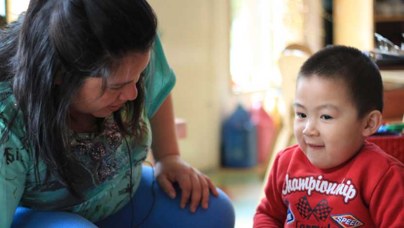 Caregiver kneeling down to level of toddler.